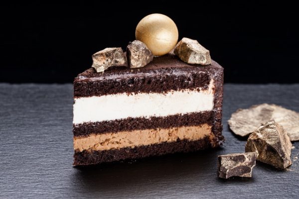 Šokoladinio biskvito tortas perteptas traškia migdoline, triufeline mase, balto šokolado ir grietinėlės kremu.